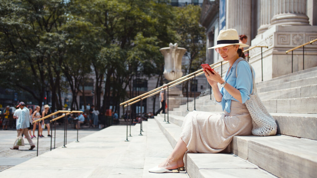 Attractive woman with phone on the steps of a building